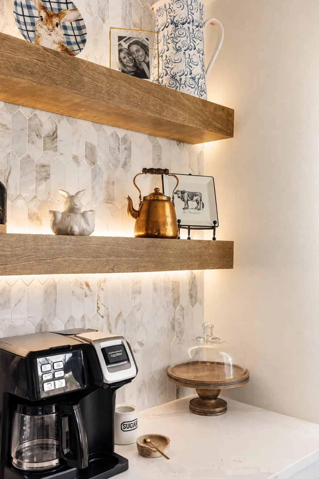 Kitchen coffee station in Tampa, FL with floating shelves and marble backsplash