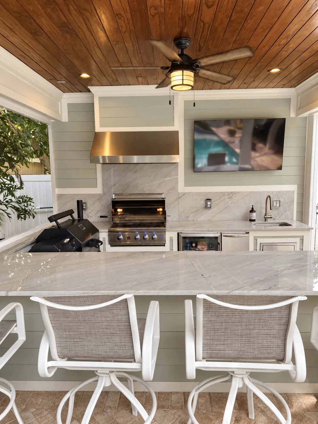 Outdoor kitchen in Tampa, FL with grill, bar seating, and TV
